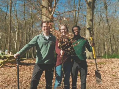 Mehr Bäume Jetzt! Drei Personen stehen mit Schaufeln im Wald