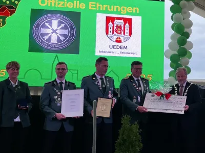 Bürgermeister Rainer Weber übergibt den symbolischen Scheck an vier Vertreter*innen der Schützenbruderschaft St. Hubertus Uedemerbruch